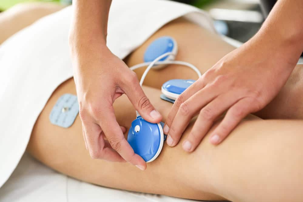 fisioterapeuta aplicando electro estimulación pierna